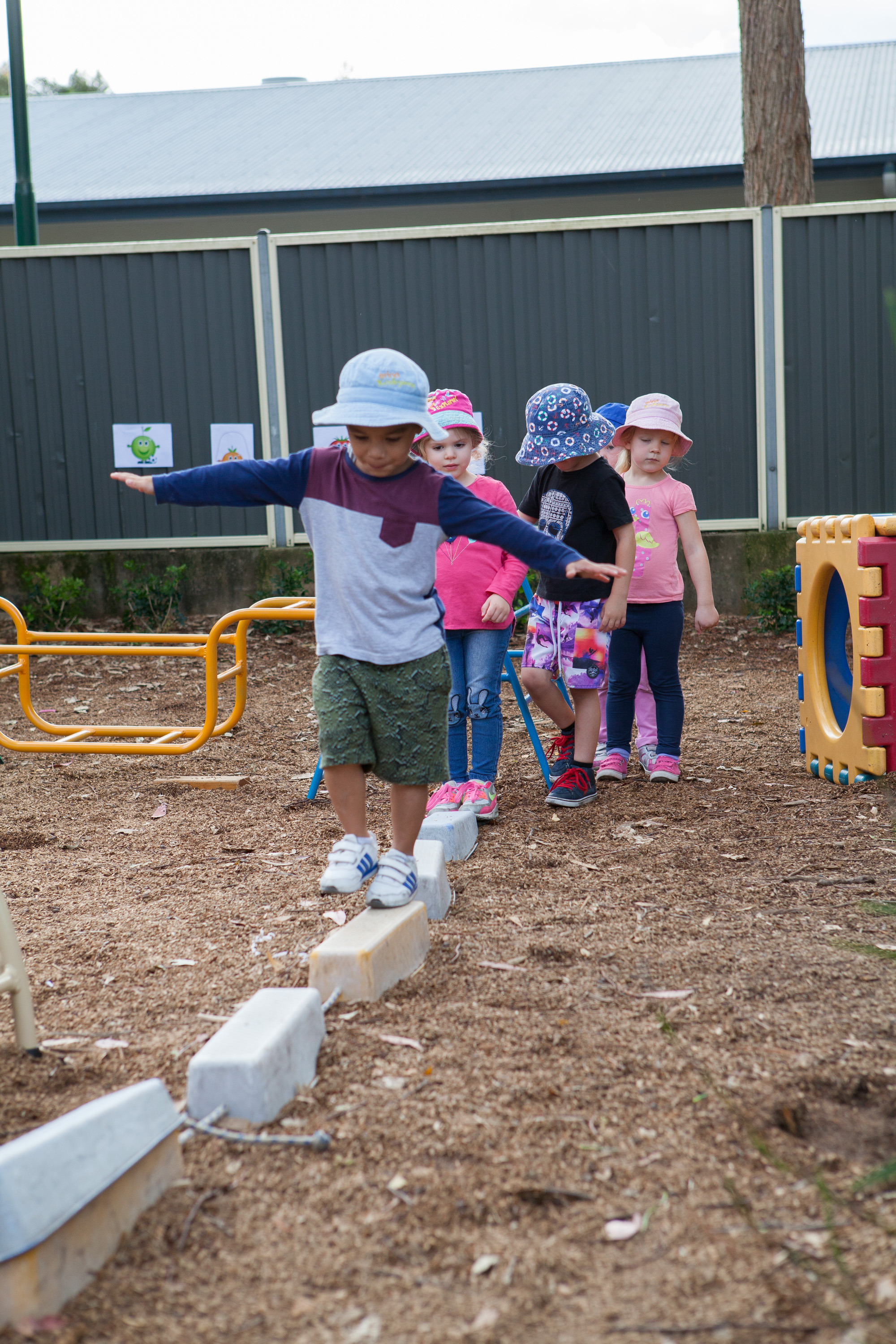 Young children balance on a balance beam