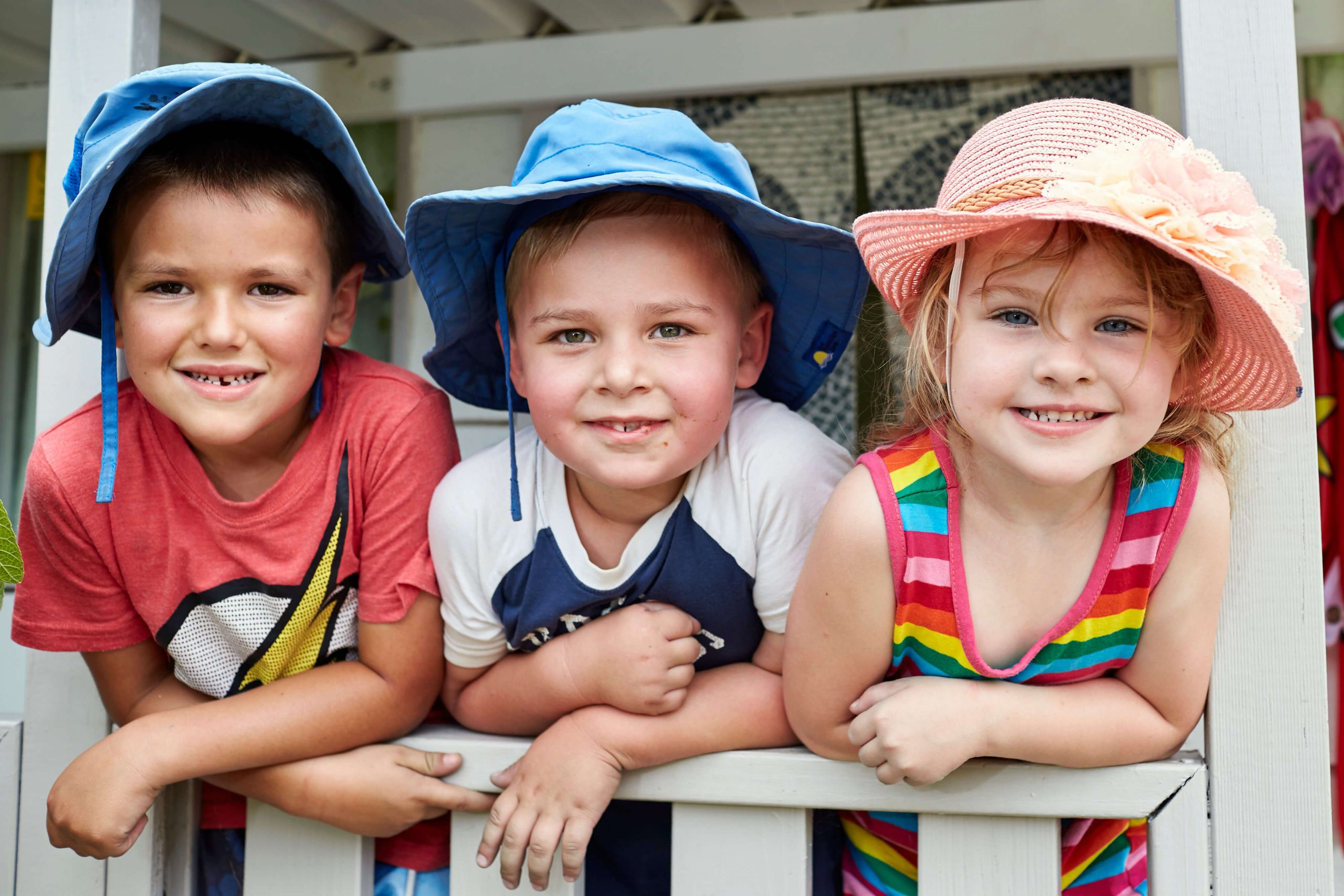 Three children smiling on a balcony